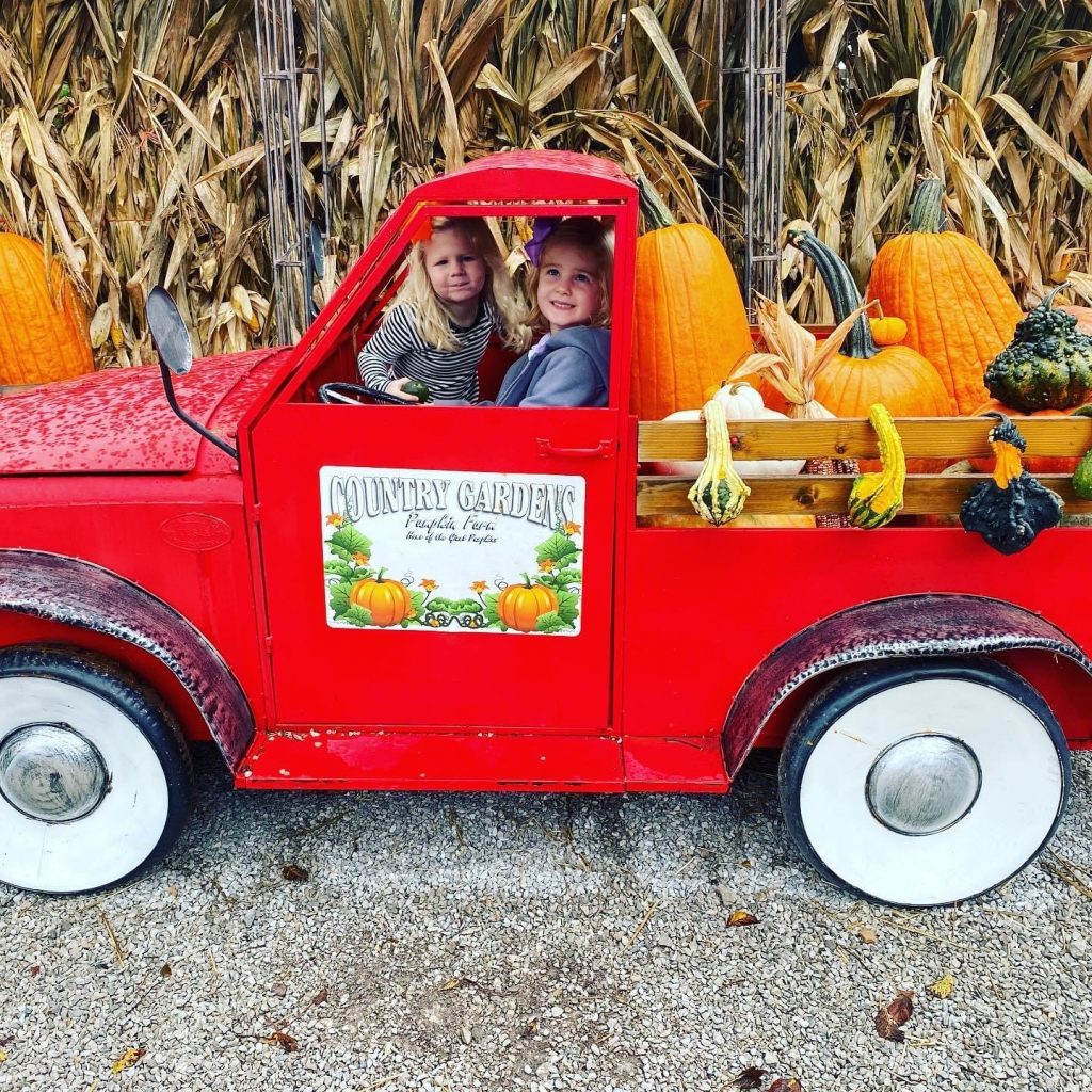 two girls in a prop truck at a pumpkin patch