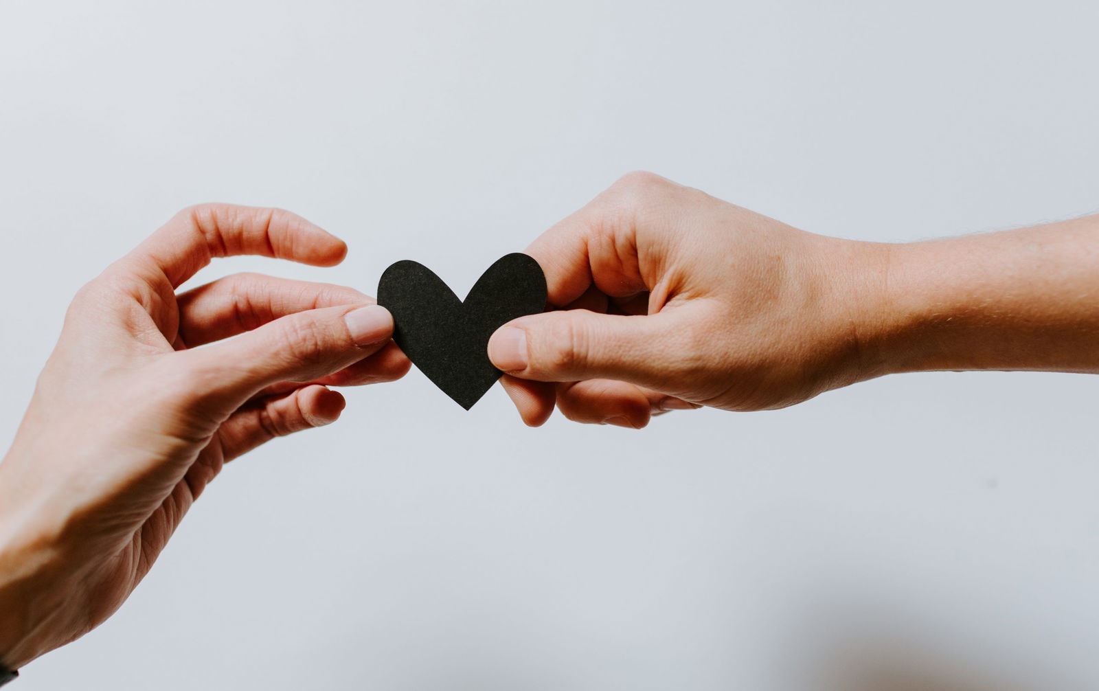 Two hands holding black heart cut out