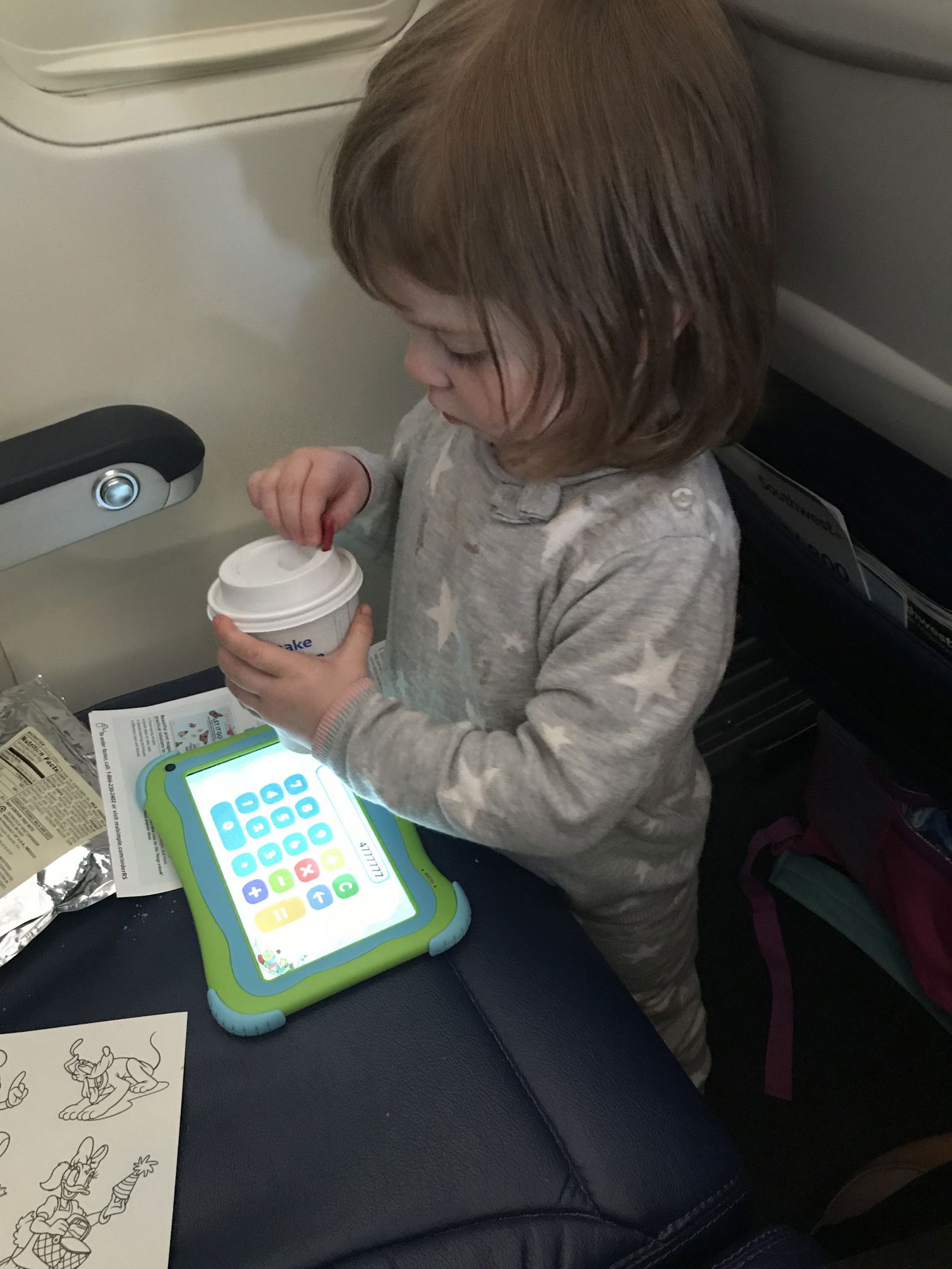 Picture of toddler with drink and toys on airplane