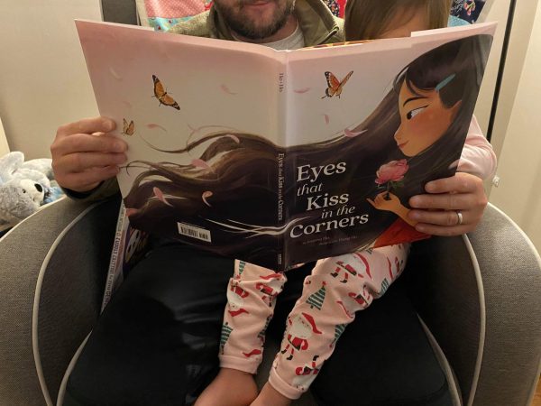 dad reading his daughter and Asian American book