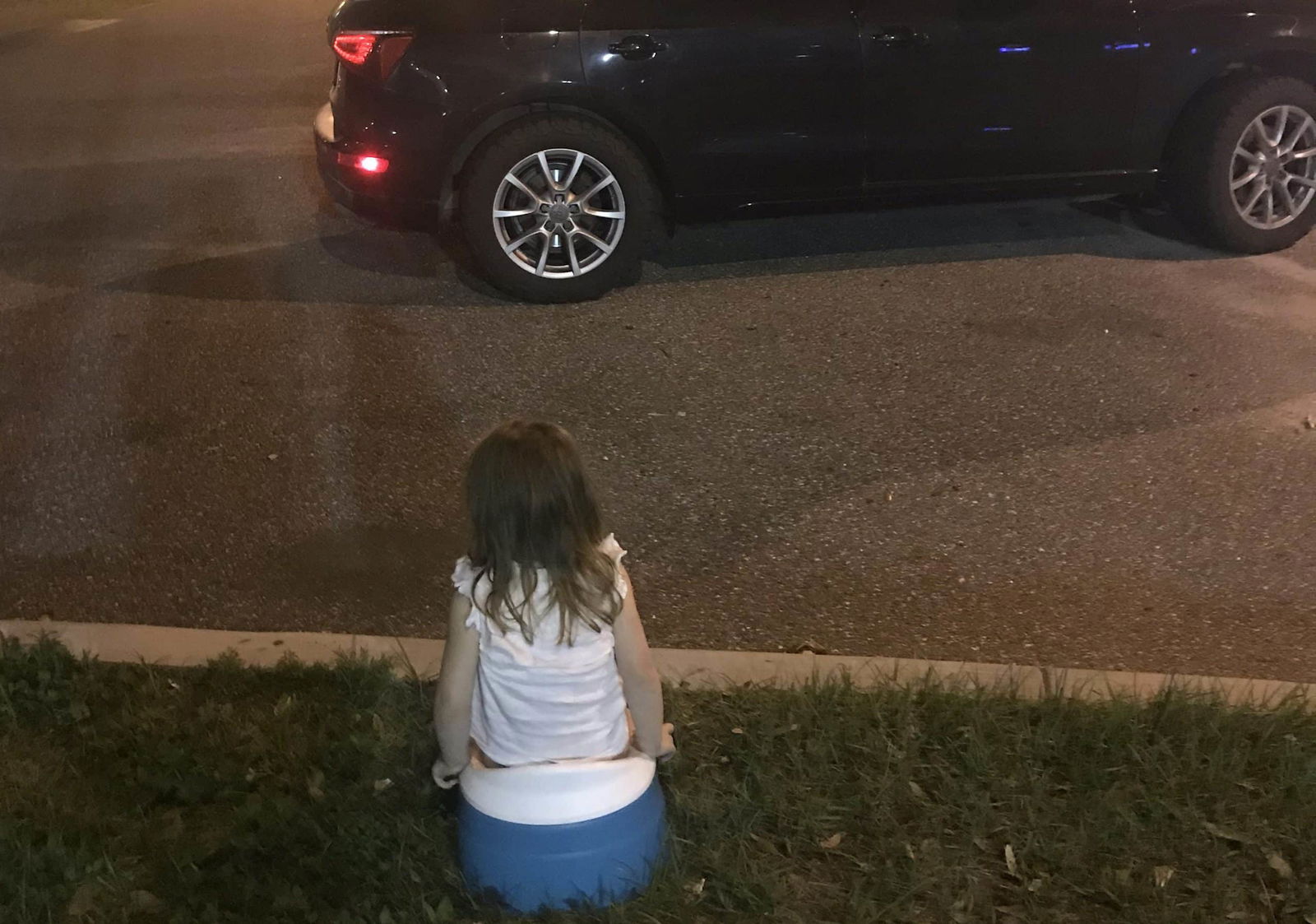 child sitting on potty in a parking lot