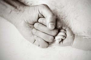 A black and white photo of an stay-at-home dad hand and baby hand are fist bumping