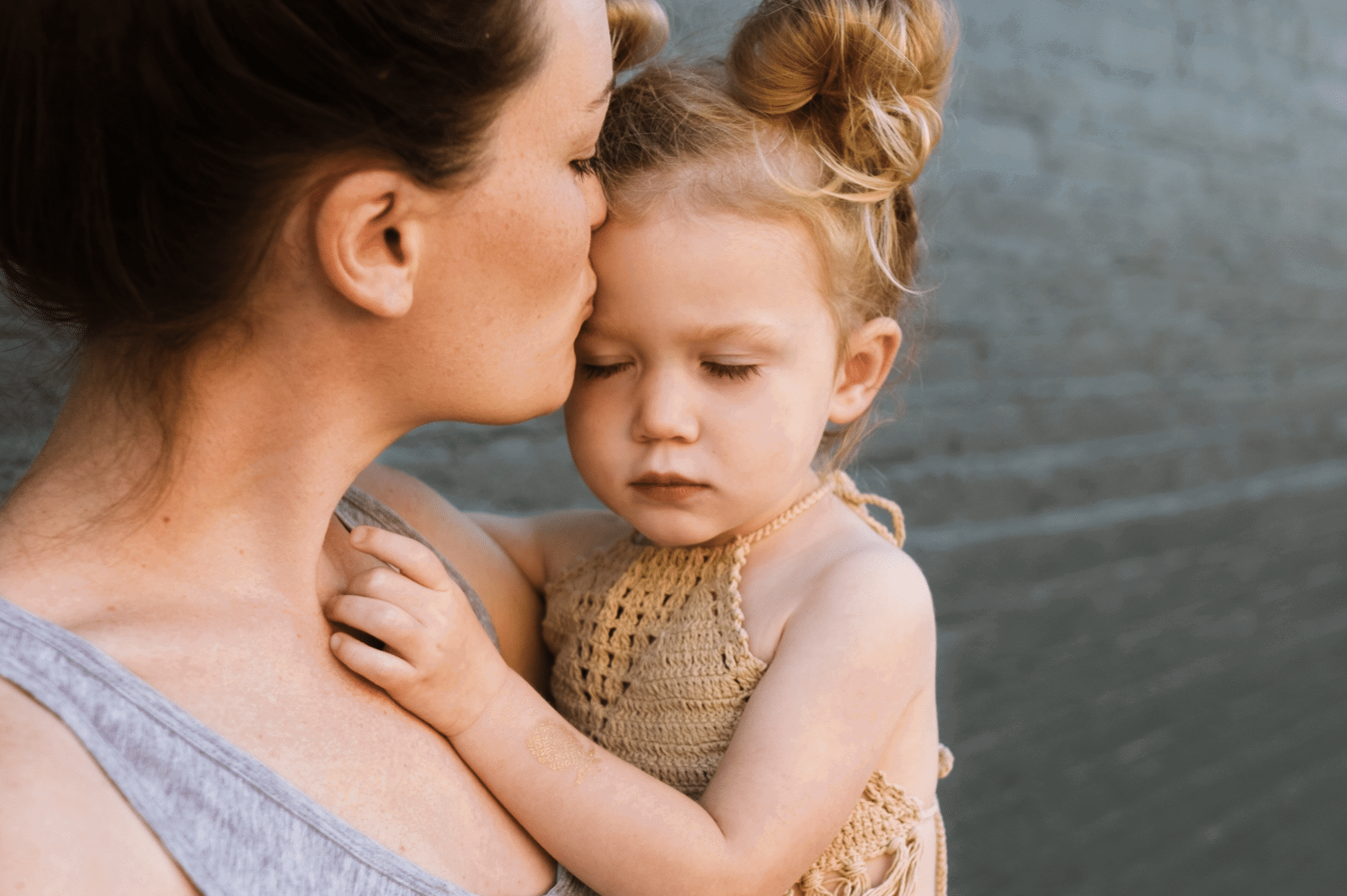 mom kissing her sad toddler