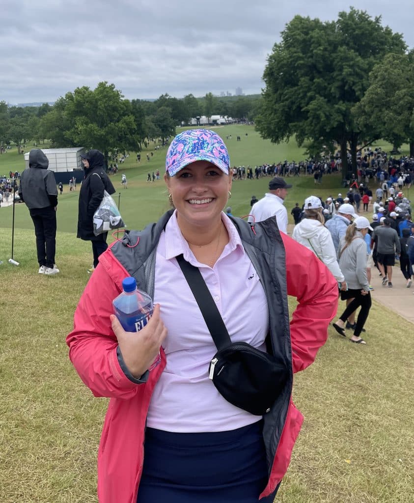 Erin wearing a black Lululemon belt bag at the PGA golf tournament. 