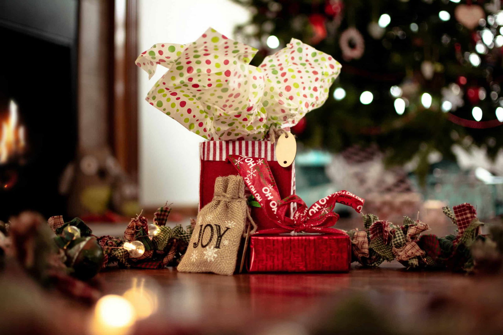 Christmas presents in the foreground with a lit christmas tree in the background, holiday magic at its finest 