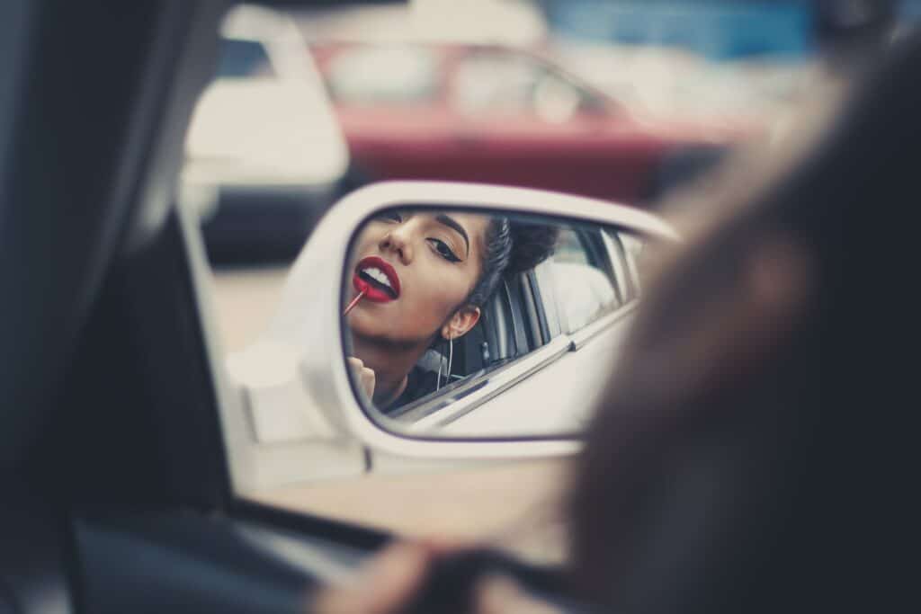 woman looking in car mirror