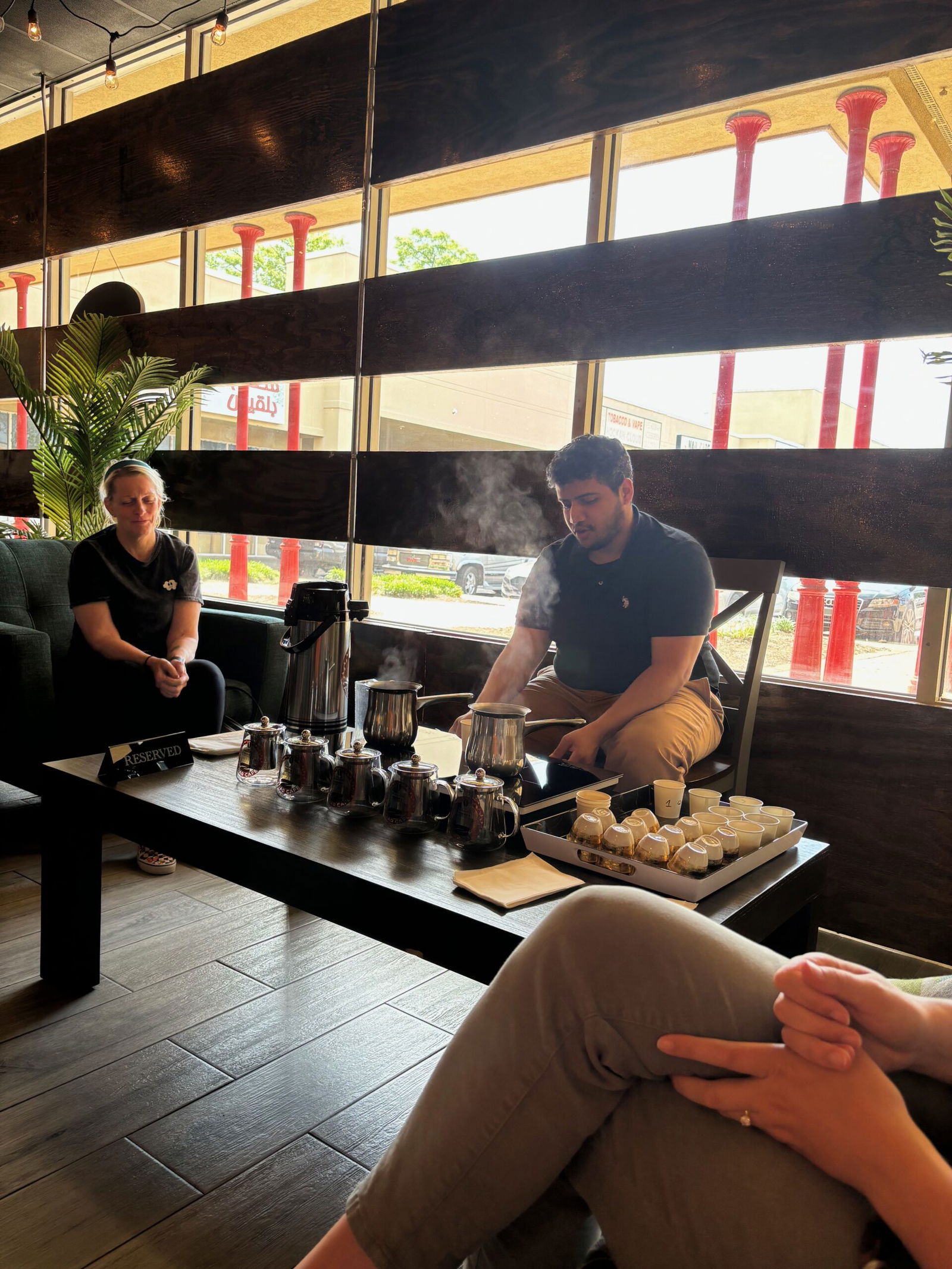 Guy pouring coffee with a display of 6 different coffees and cups in front of him