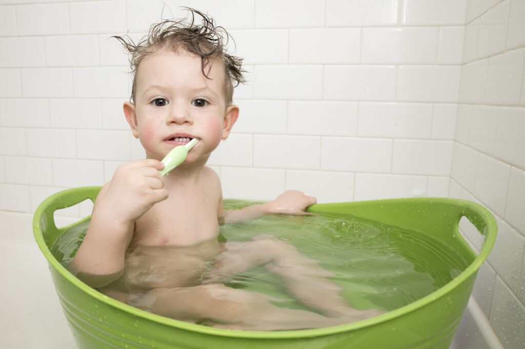 toddler brushing their teeth in the bath