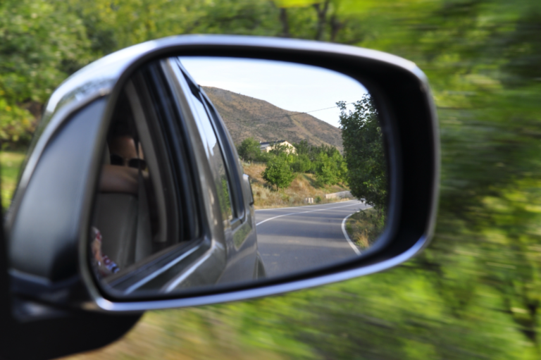 looking out the side mirror of a car on a road trip